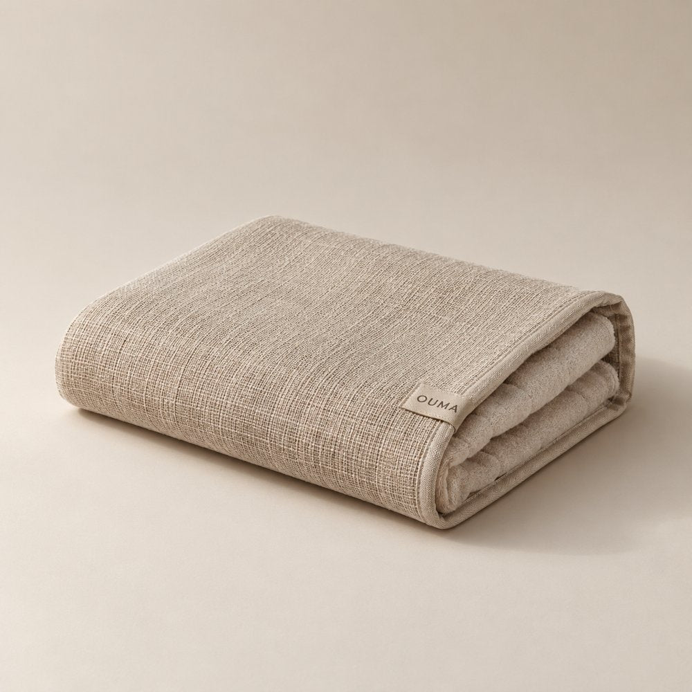 Folded beige OUMA sauna sitting towel with two textile textures — AI-generated concept.